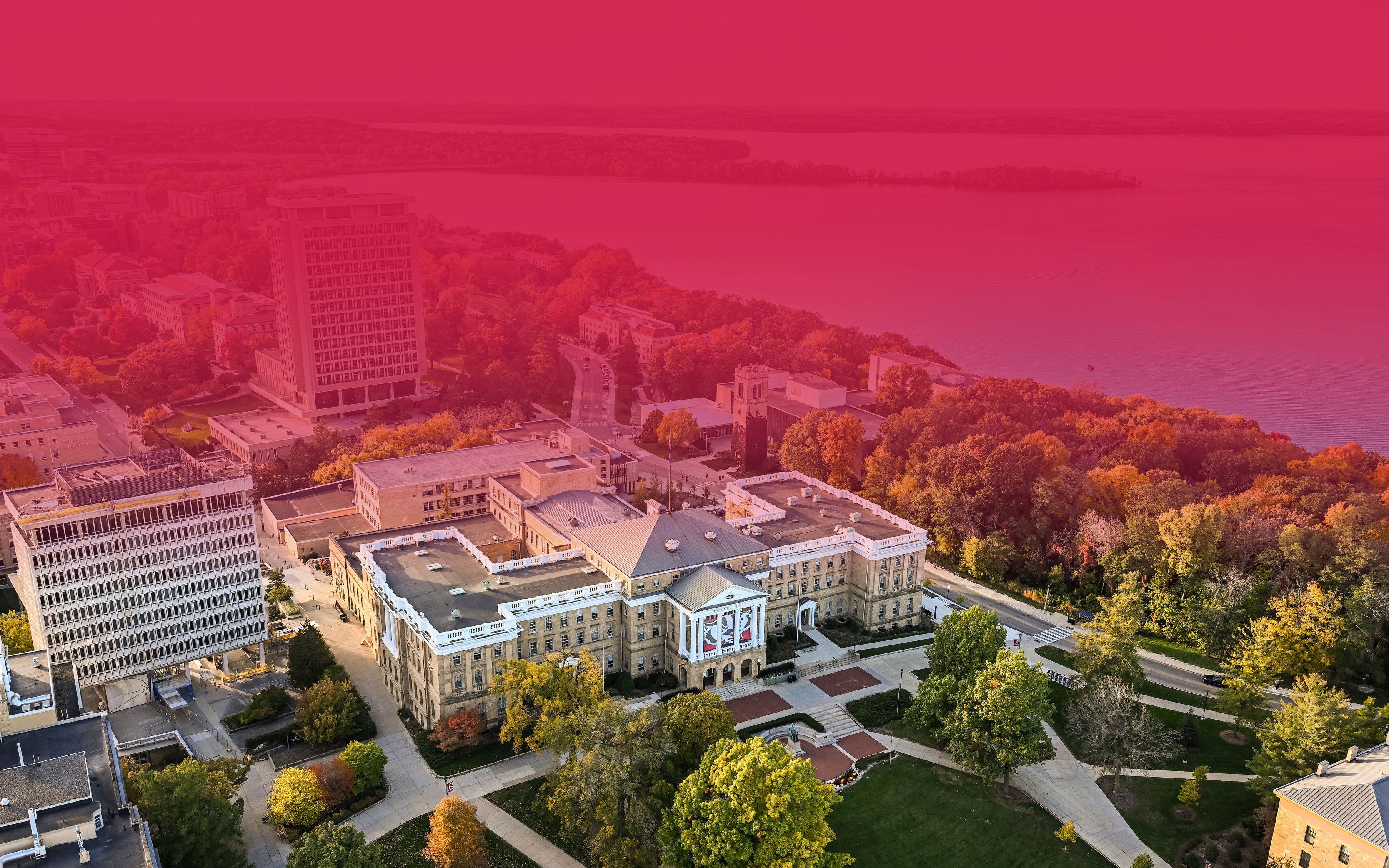 Aerial image of Bascom Hall and central UW–Madison campus during a sunny autumn day. Top half of the image features a red tint overlay with text.
